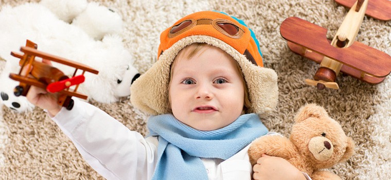 Young child laying on the carpet on his back.