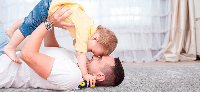 Father laying on his back holding his son.